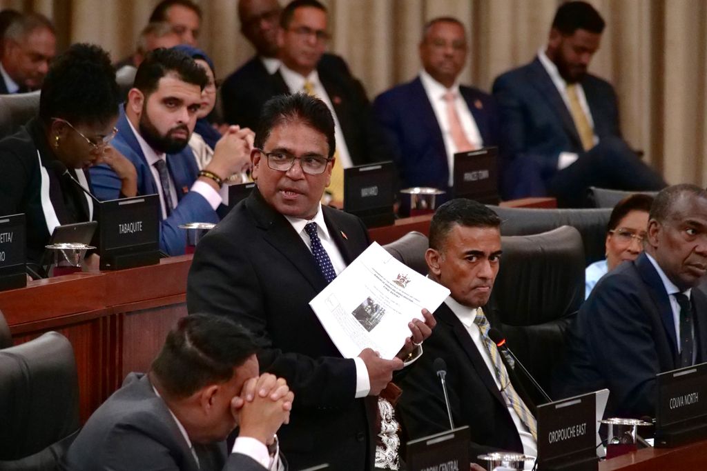 Minister of Energy Dr Roodal Moonilal holds a copy of the NiQuan report in Parliament yesterday.