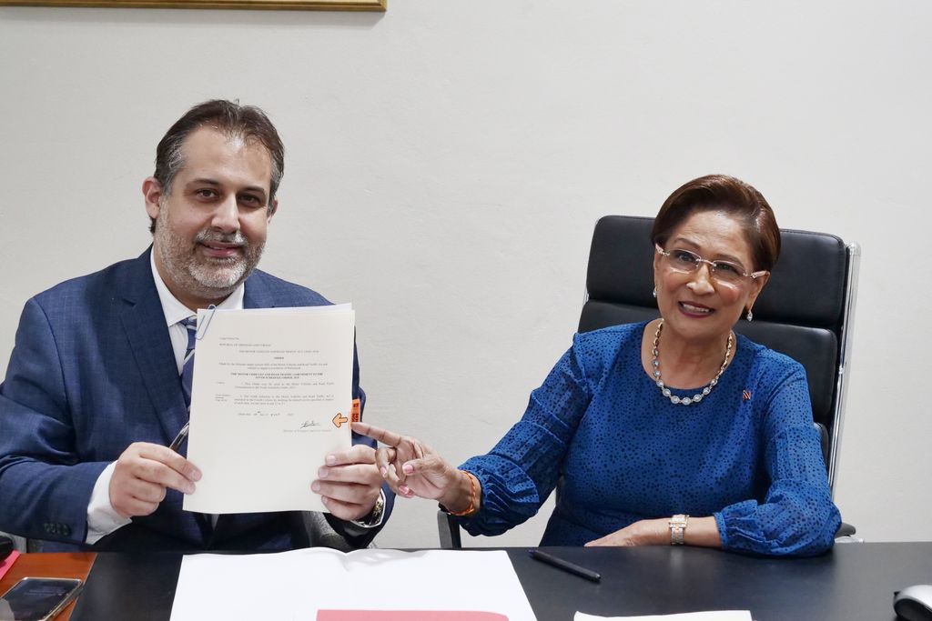 Minister of Transport and Civil Aviation Eli Zakour and Prime Minister Kamla Persad-Bissessar show the Cabinet-approved document to remove specific conditions from the demerit points system to members of the media at yesterday’s post-Cabinet media briefing. 