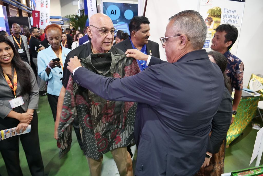 Minister of Planning, Economic Affairs & Development for Trinidad and Tobago, Senator Kennedy Swaratsingh, centre, checks to see if a shirt fits Minister of Trade, Investment & Tourism Satyakama “Kama” Maharaj during day two of the Trinidad & Tobago International Trade and Investment Convention (TIC) 2025 held at the Centre of Excellence in Macoya yesterday. 