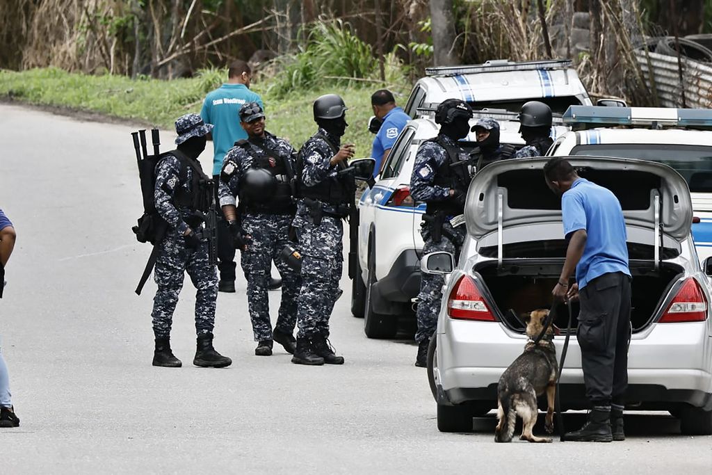 A canine handler uses his police dog to search the trunk of a car during a joint exercise at Heights of Guanapo yesterday.